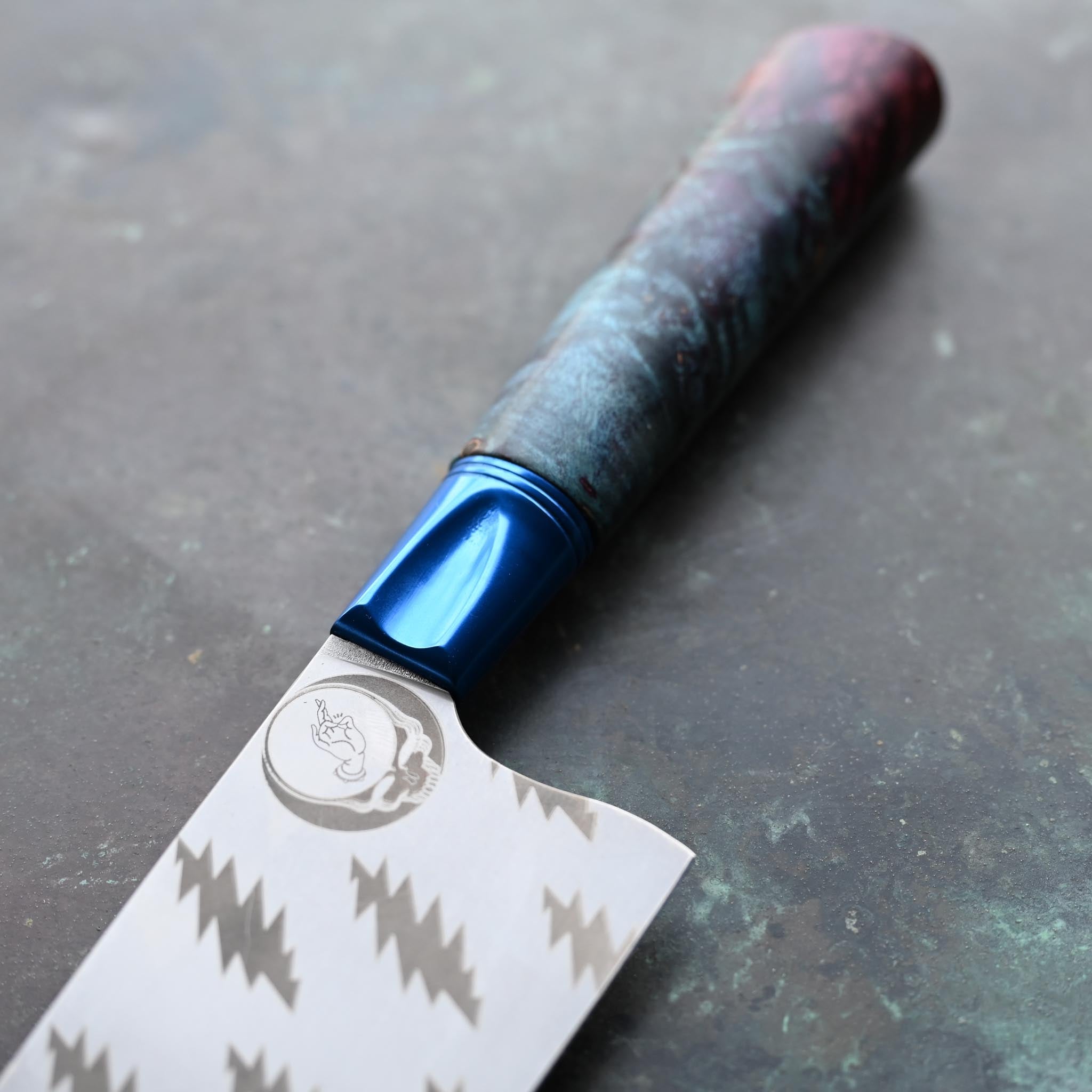 GRATEFUL DEAD CHEF KNIFE, BLUE BOLSTER, TIE DYE WOOD HANDLE, ON CONCRETE